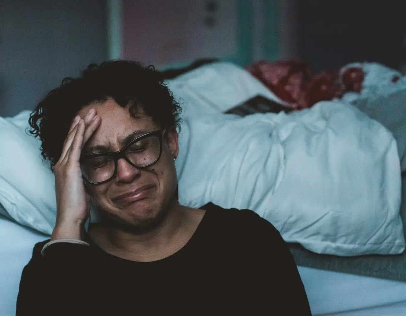 Person crying at the side of their bed