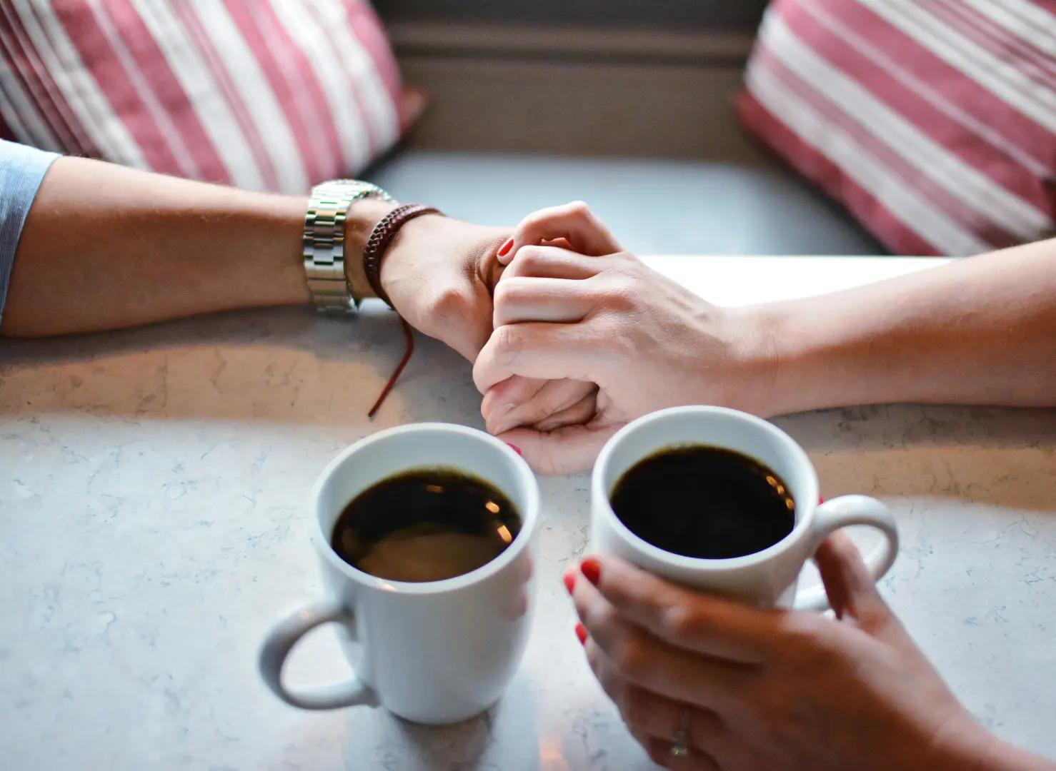 Couple holding hands while drinking a cup of coffee