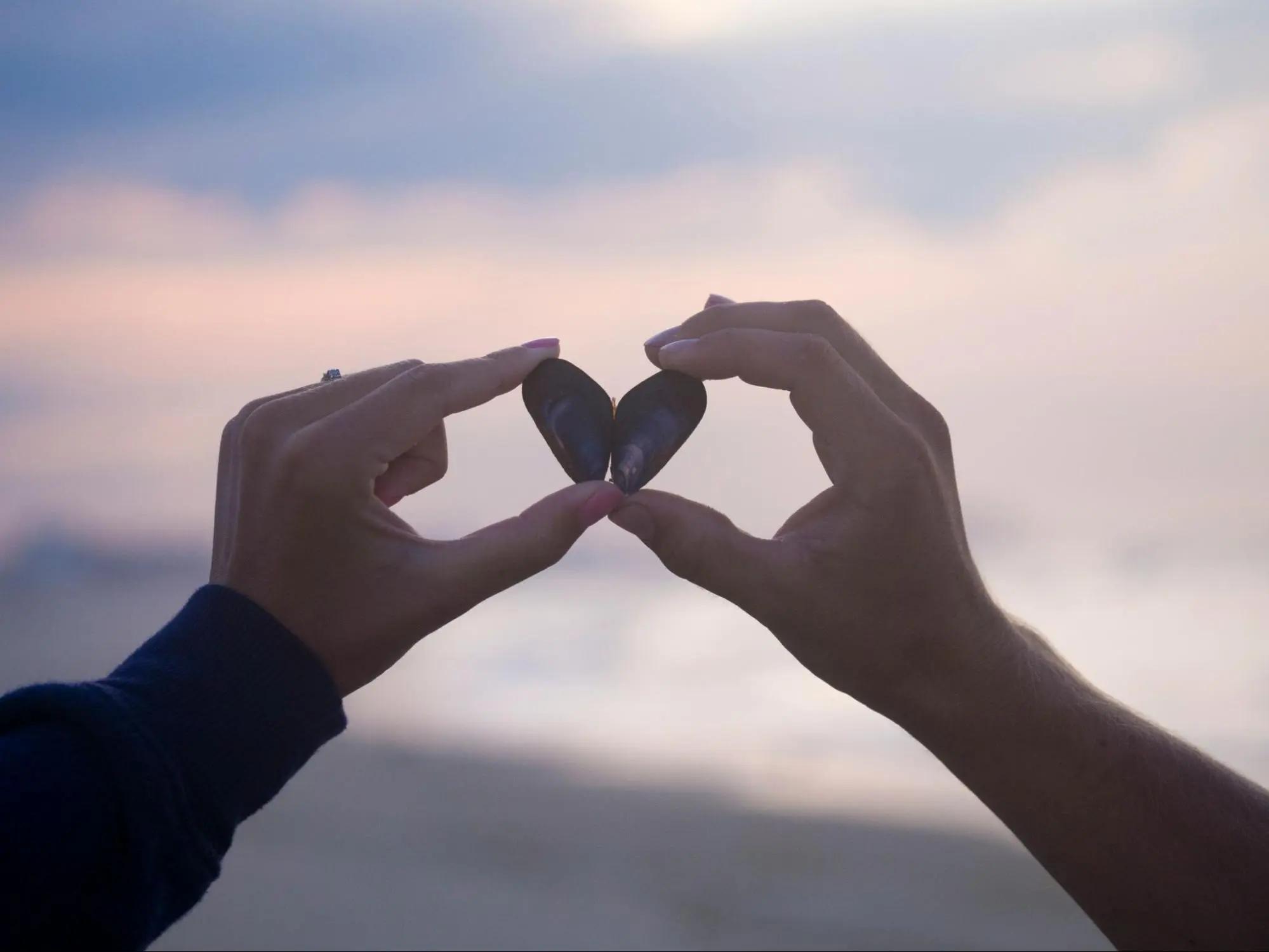 couple making a heart using pebbles