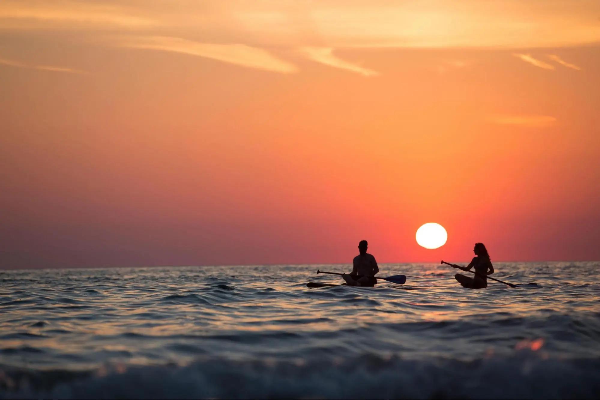 Couple paddleboarding during a sunset at the beach