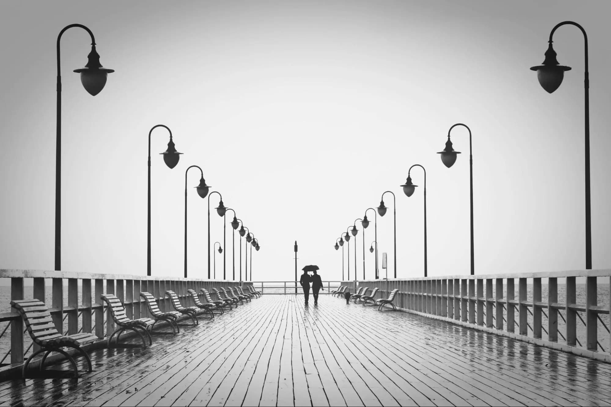 Couple walking on a wooden dock under an umbrella