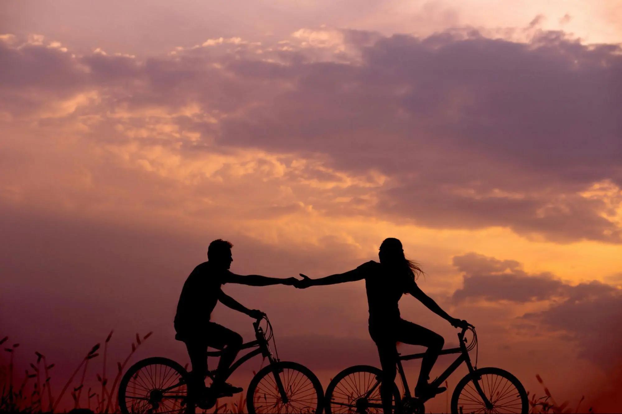 Silhouette of a couple riding bicycles against a sunset