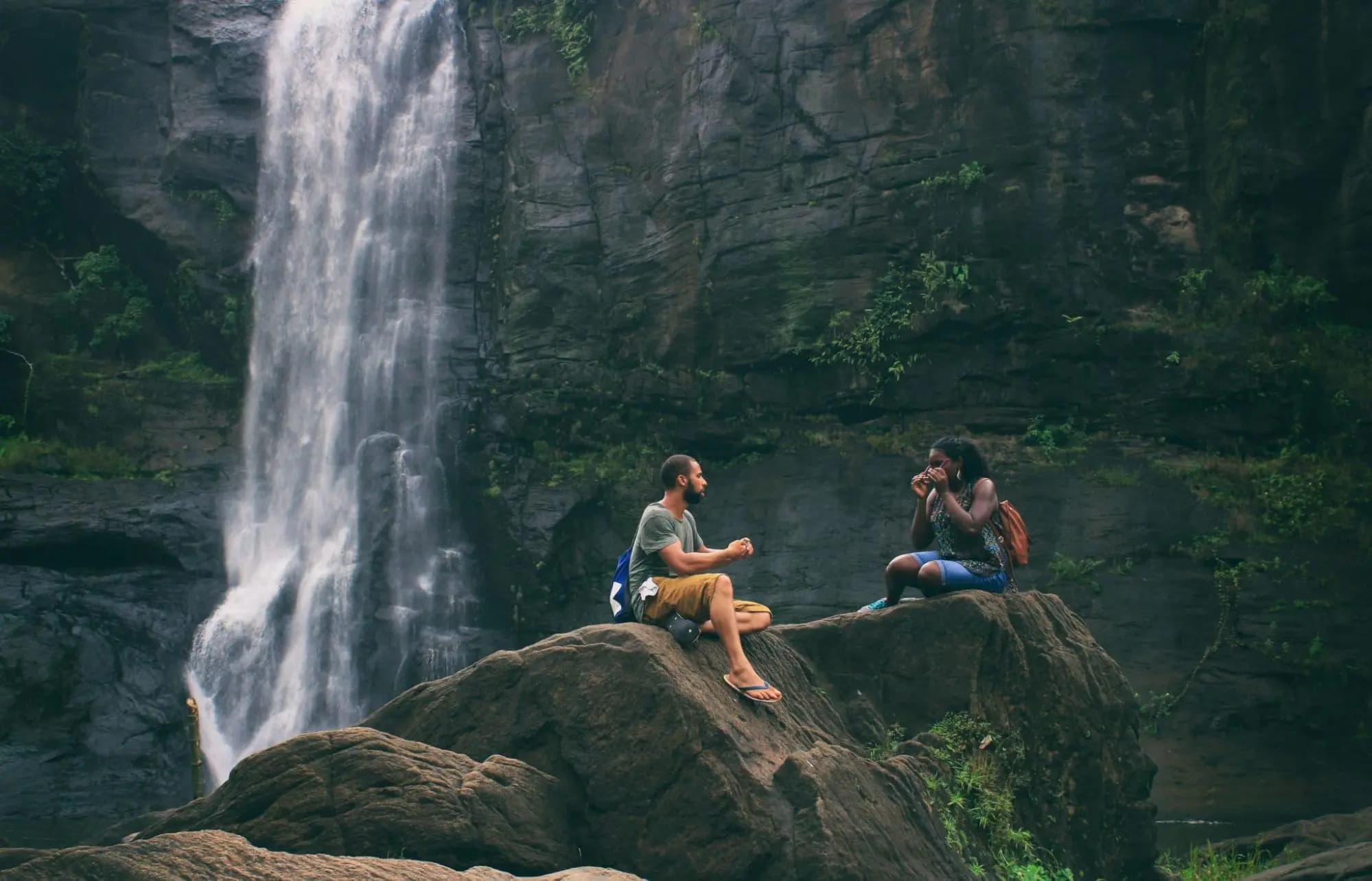 Couple sitting on a rock close to a waterfall